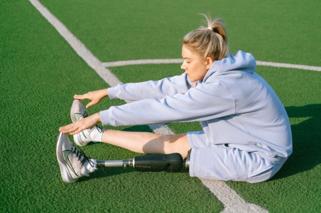 focused disabled woman stretching body on stadium